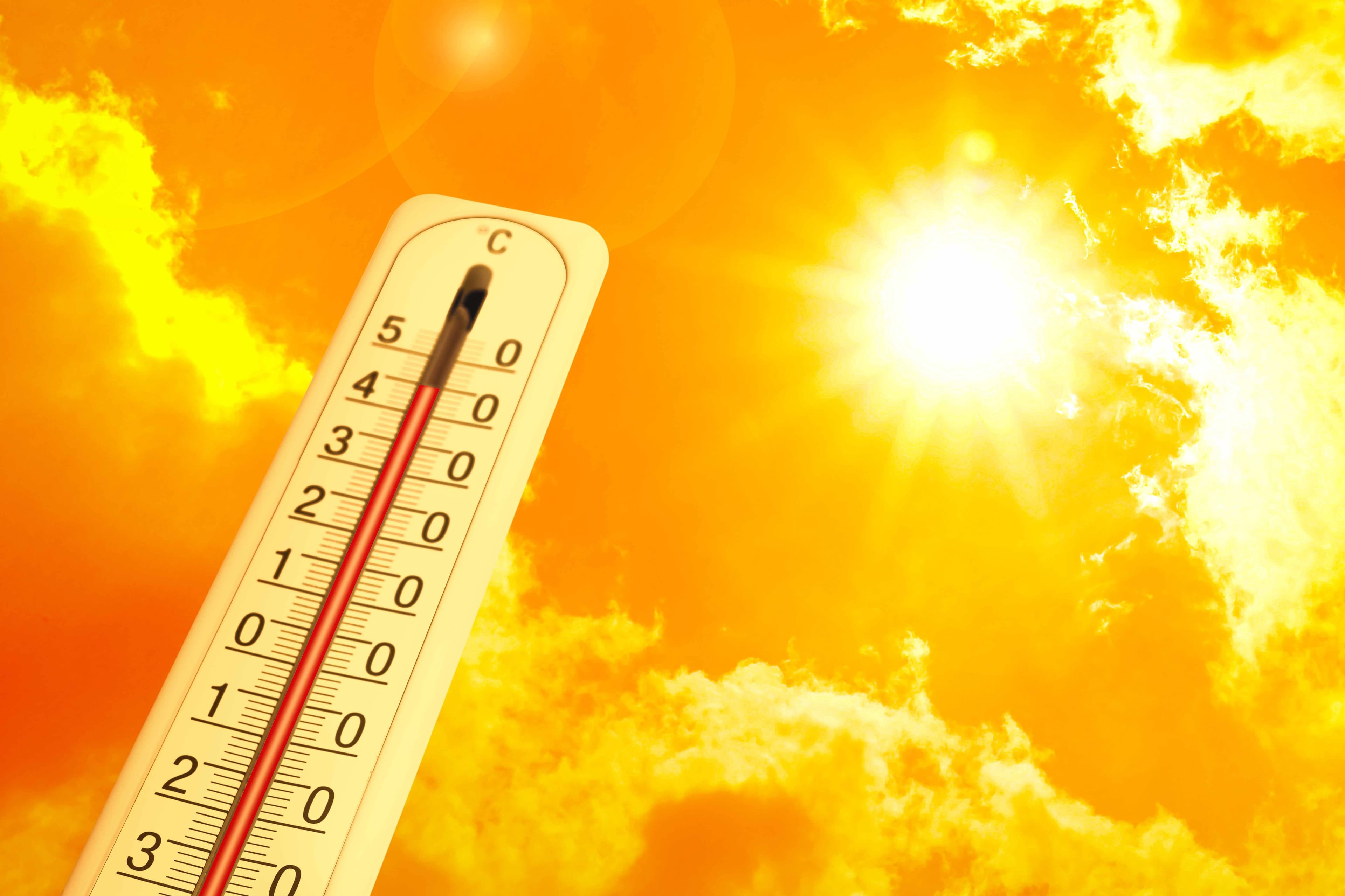 A thermometer reading well above 40 degrees Celsius against a bright orange summer sky