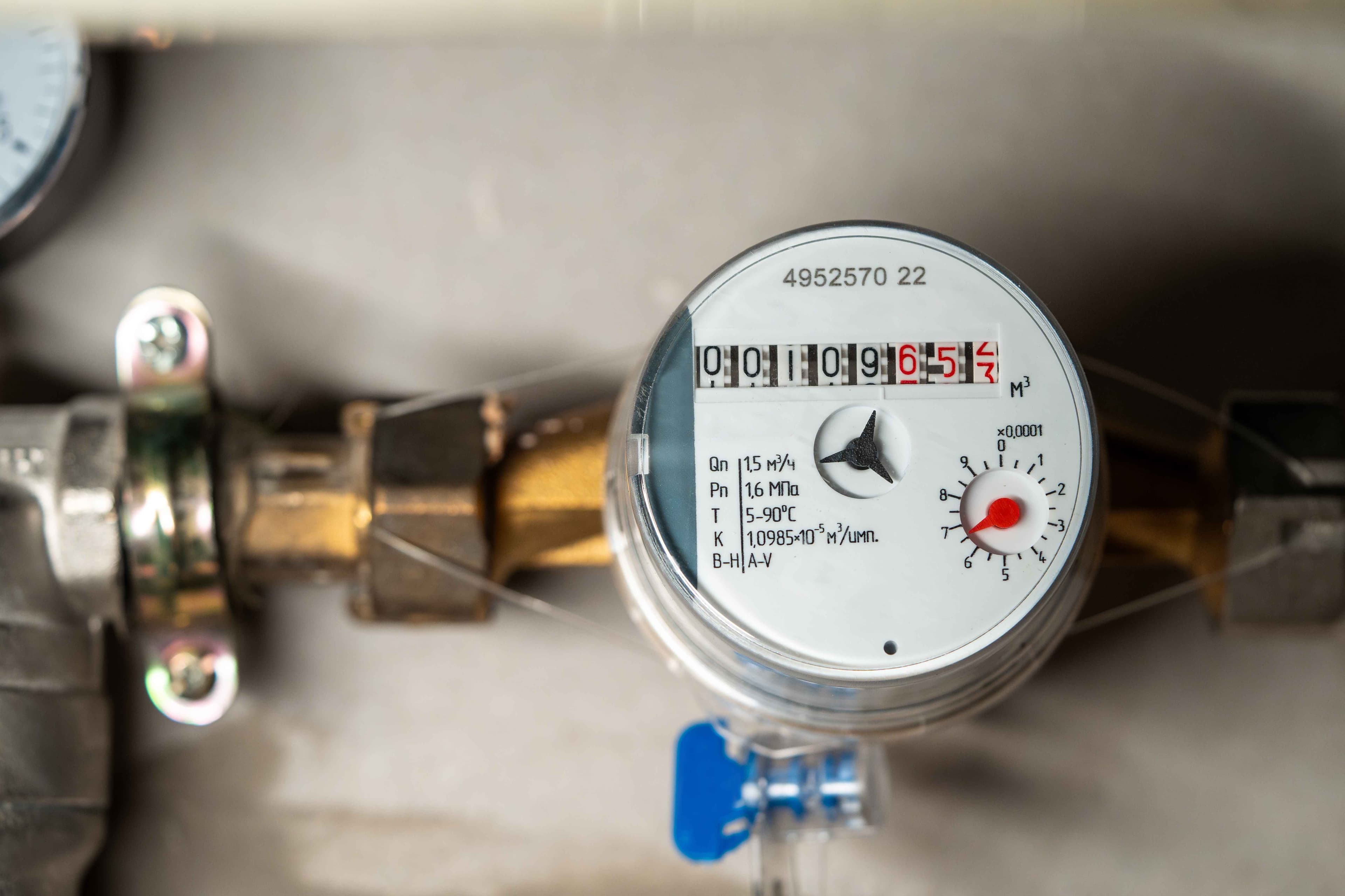 Close-up of a residential water meter and pressure gauge on an exposed pipe