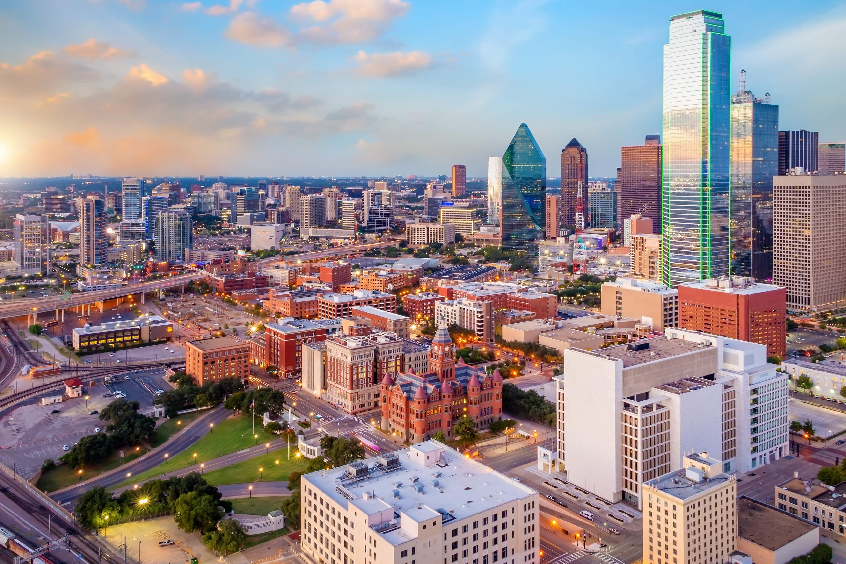 Aerial view of the downtown Dallas skyline with illuminated skyscrapers at dusk