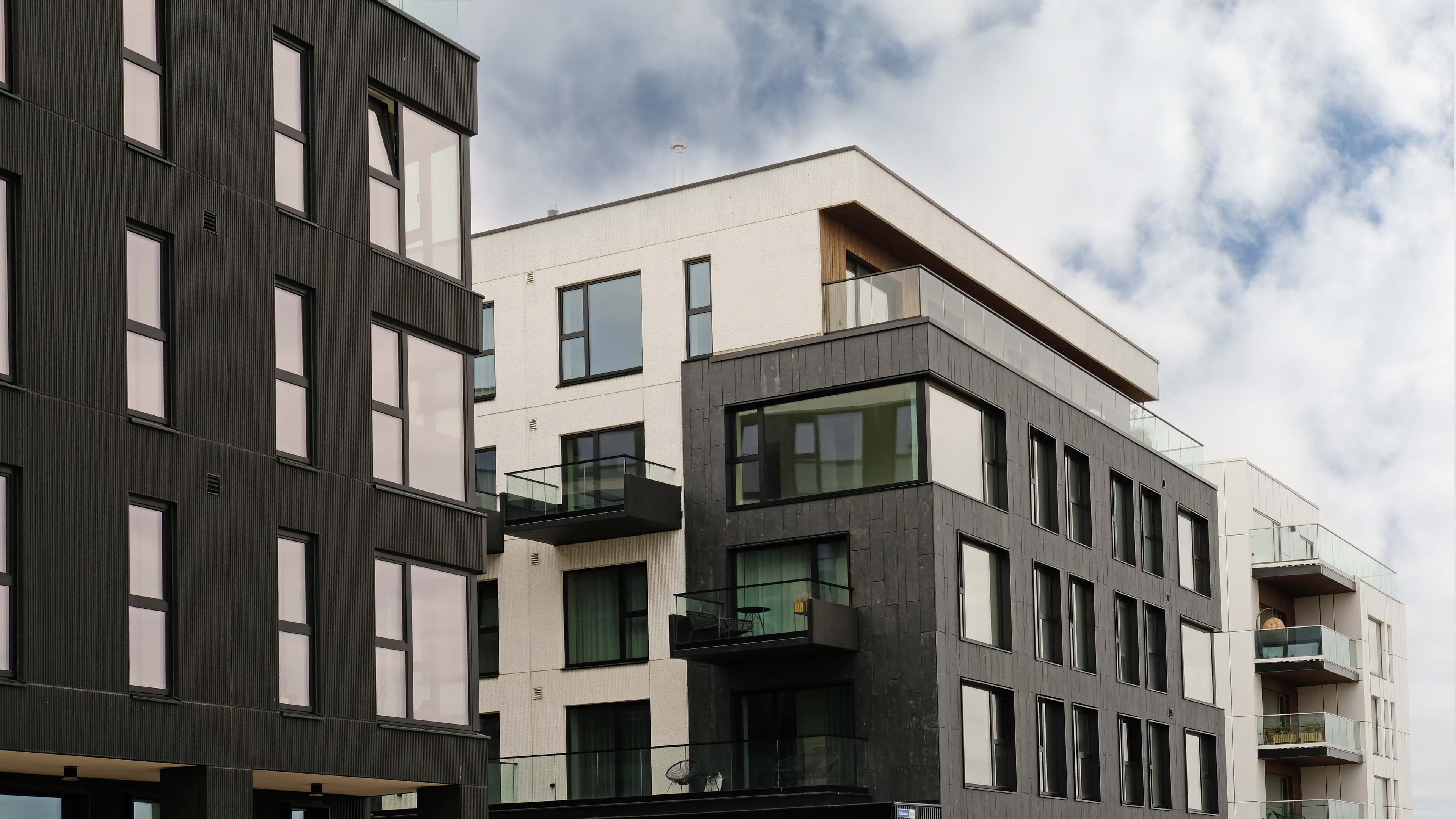 Modern multi-unit apartment building exterior with dark paneling, white trim, and private balconies