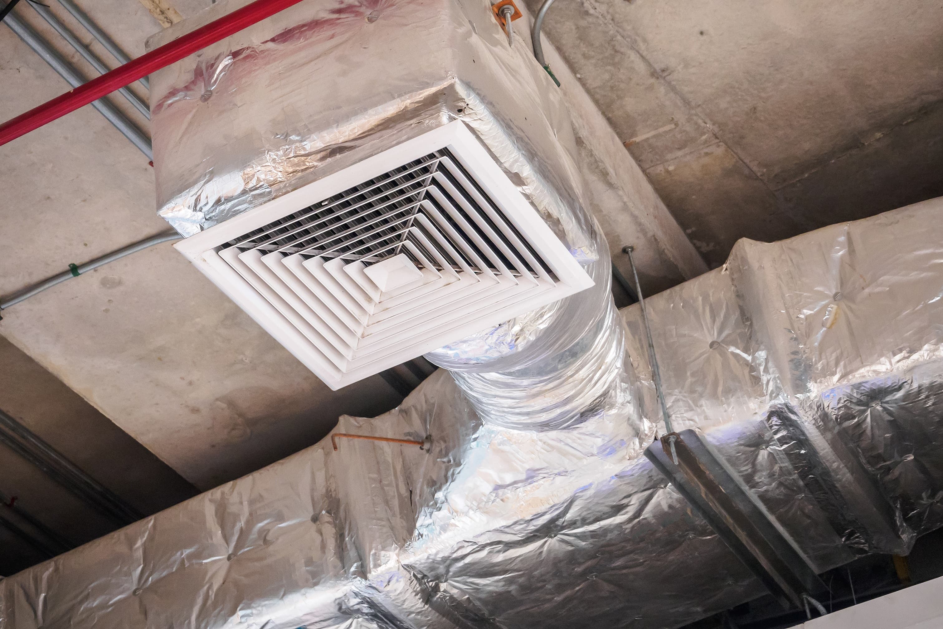 A ceiling supply vent diffuser connected to insulated ductwork, the type of register and accessible duct run covered by air duct cleaning and maintenance.
