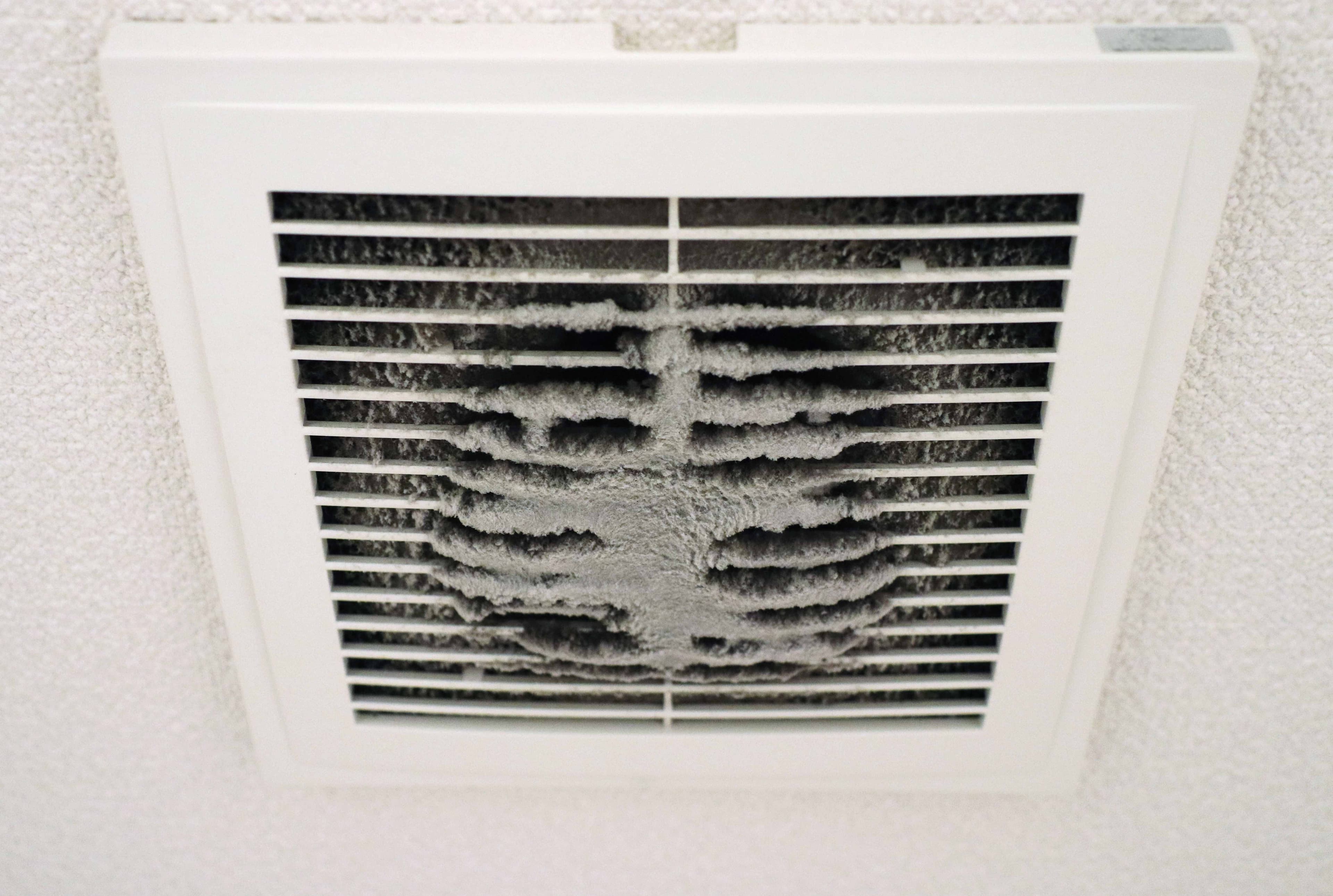 Visible dust buildup accumulated on the slats of a ceiling vent register.