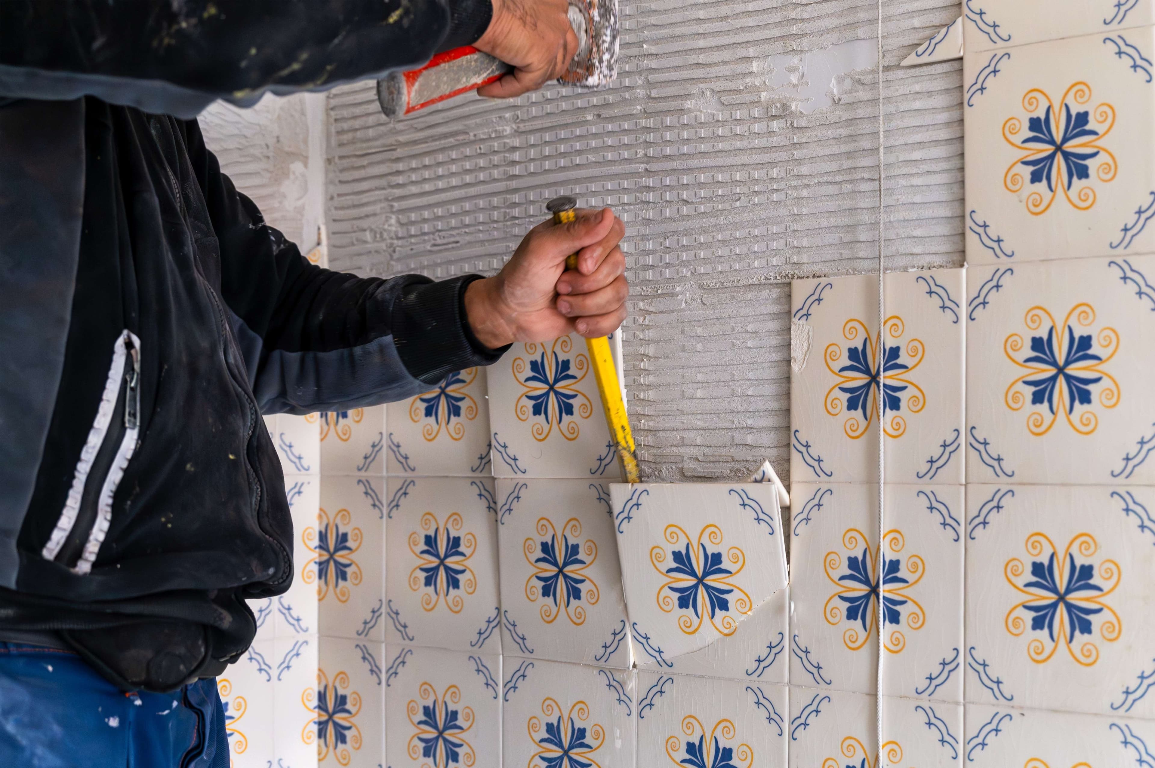 Installer applying adhesive for patterned bathroom wall tile