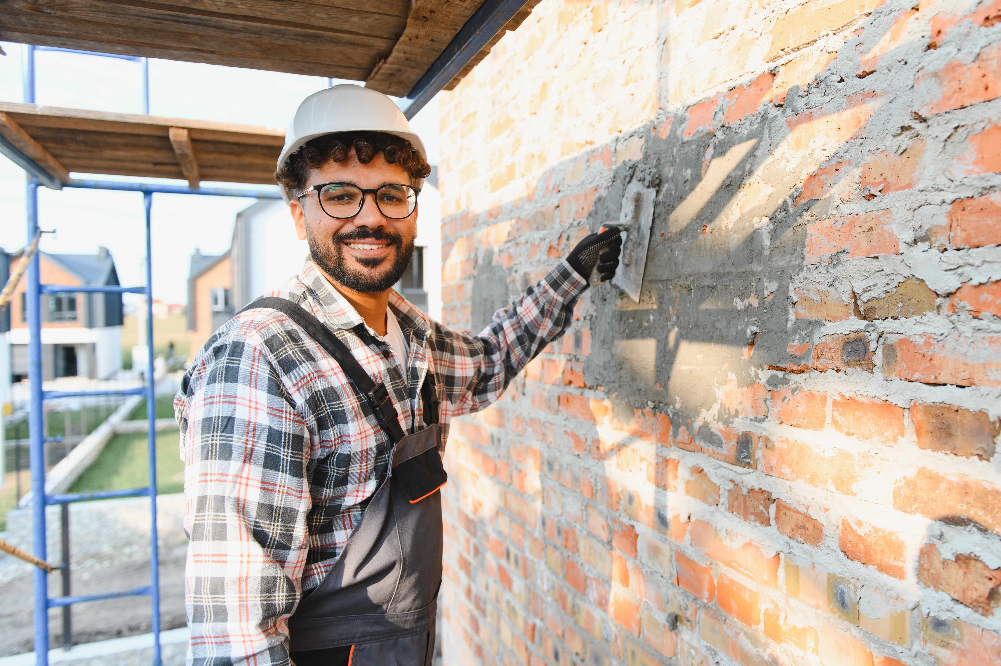 Mason smoothing fresh mortar onto a brick wall with a trowel