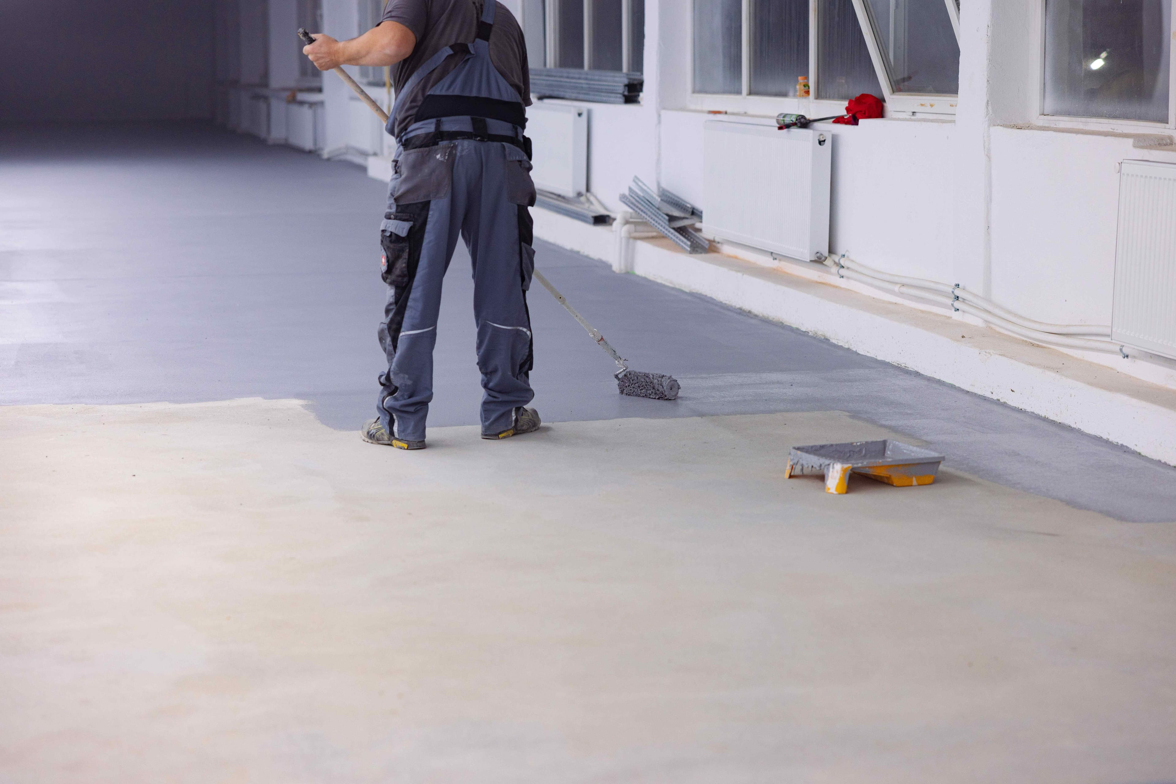 Worker applying a finish to an indoor concrete floor