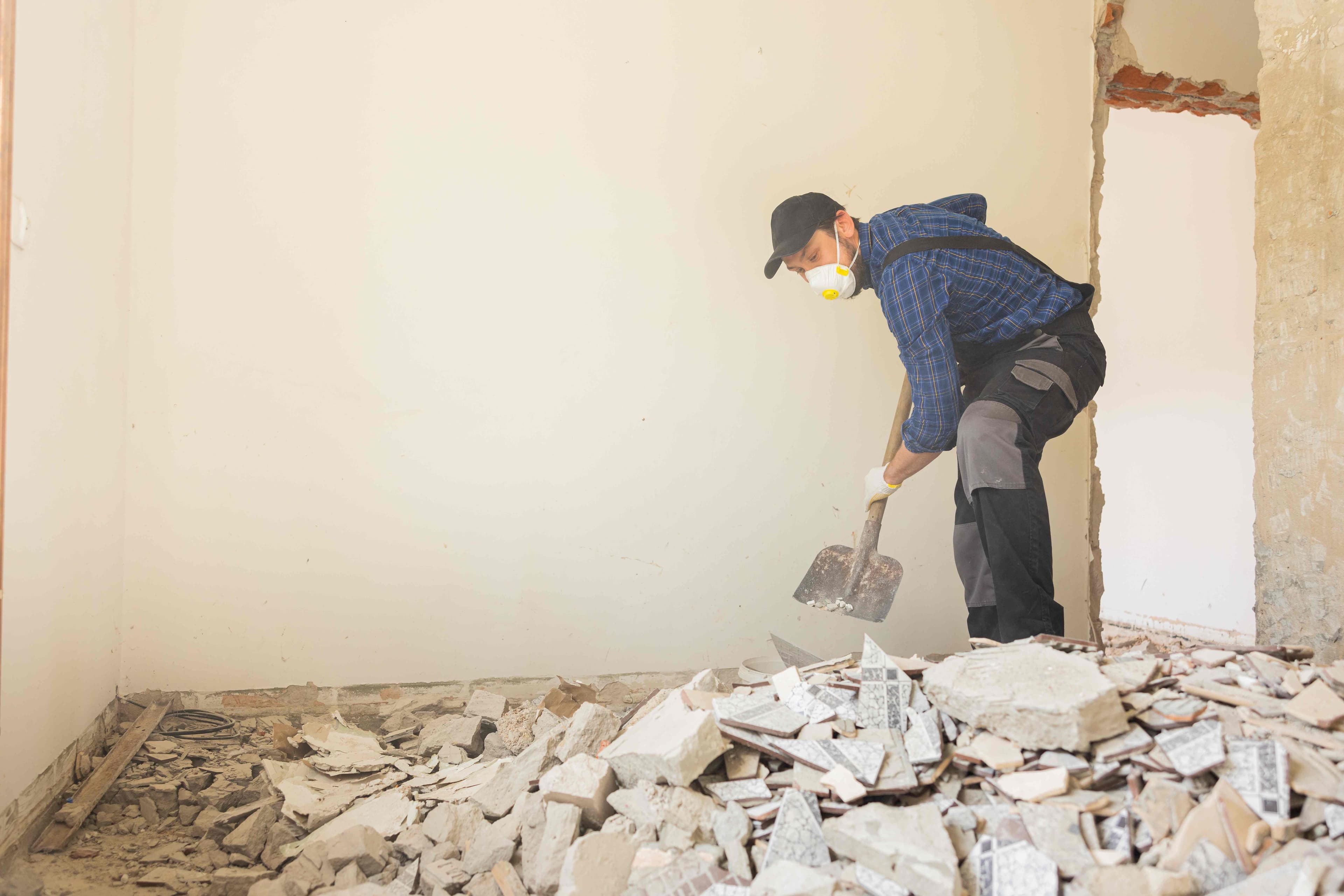 Worker shoveling tile debris during an interior room cleanout