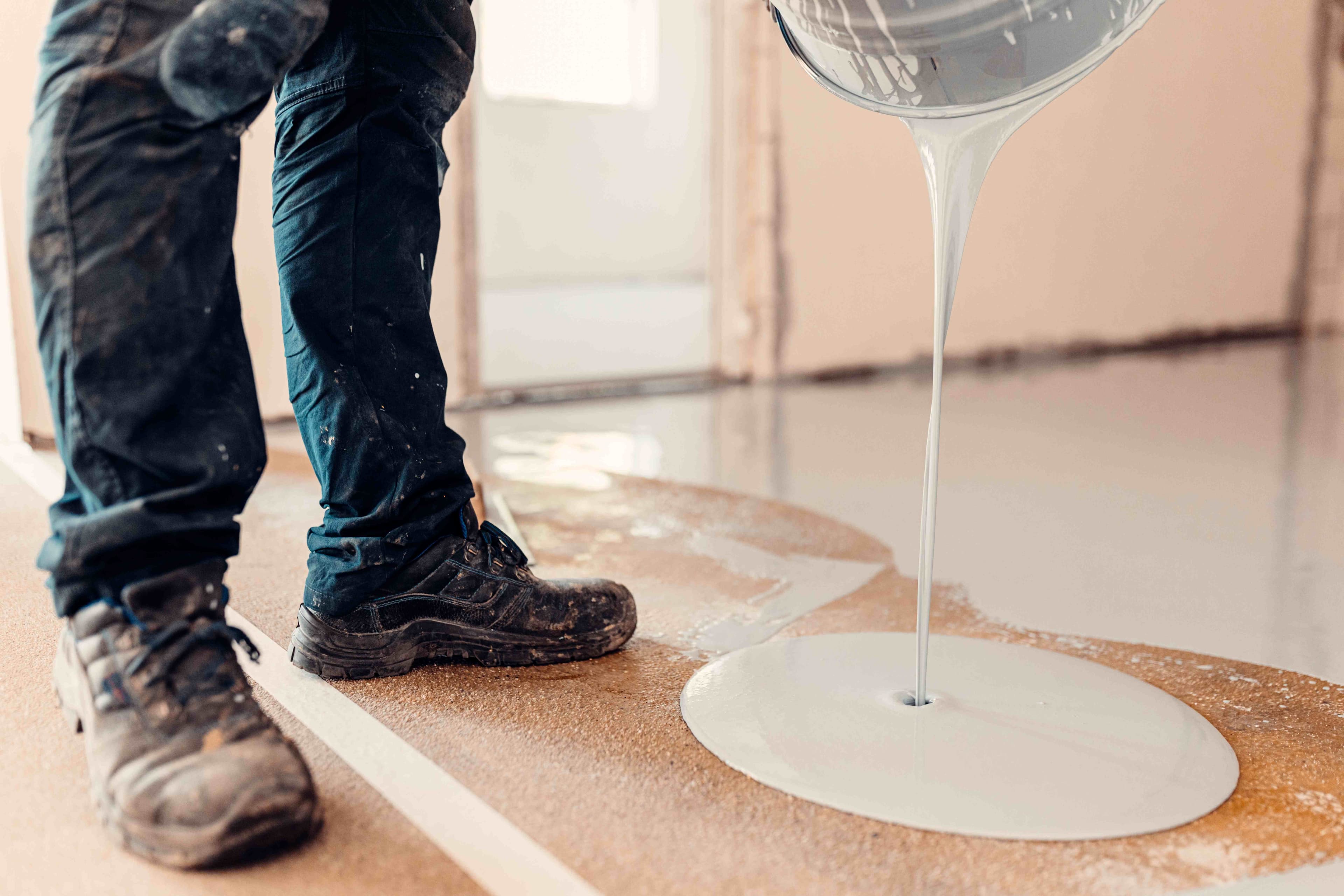 Self-leveling epoxy coating being poured onto a concrete floor