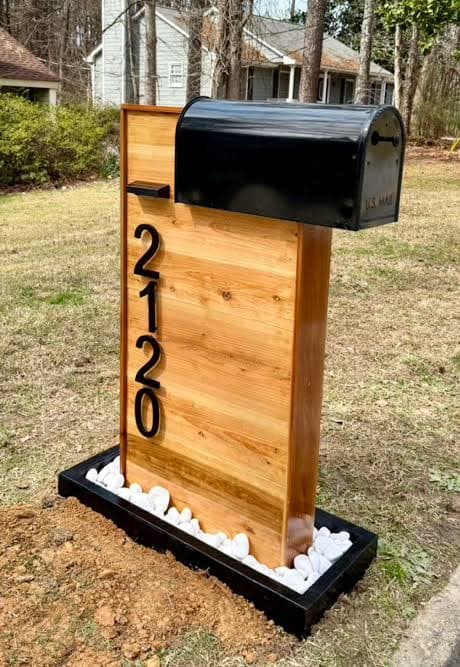 Black residential mailbox mounted on a post with a stone base