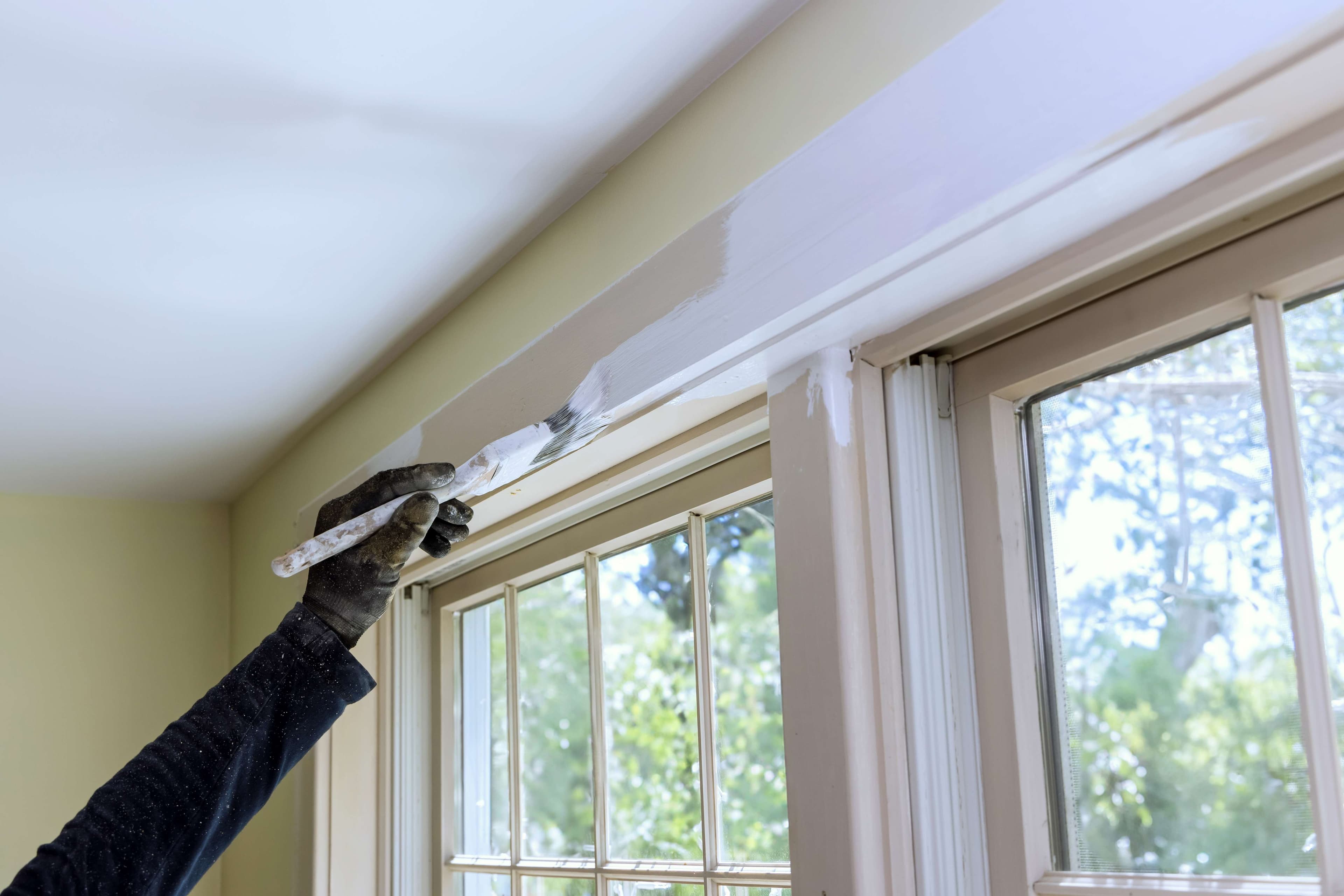 Painter applying finish paint to interior ceiling trim