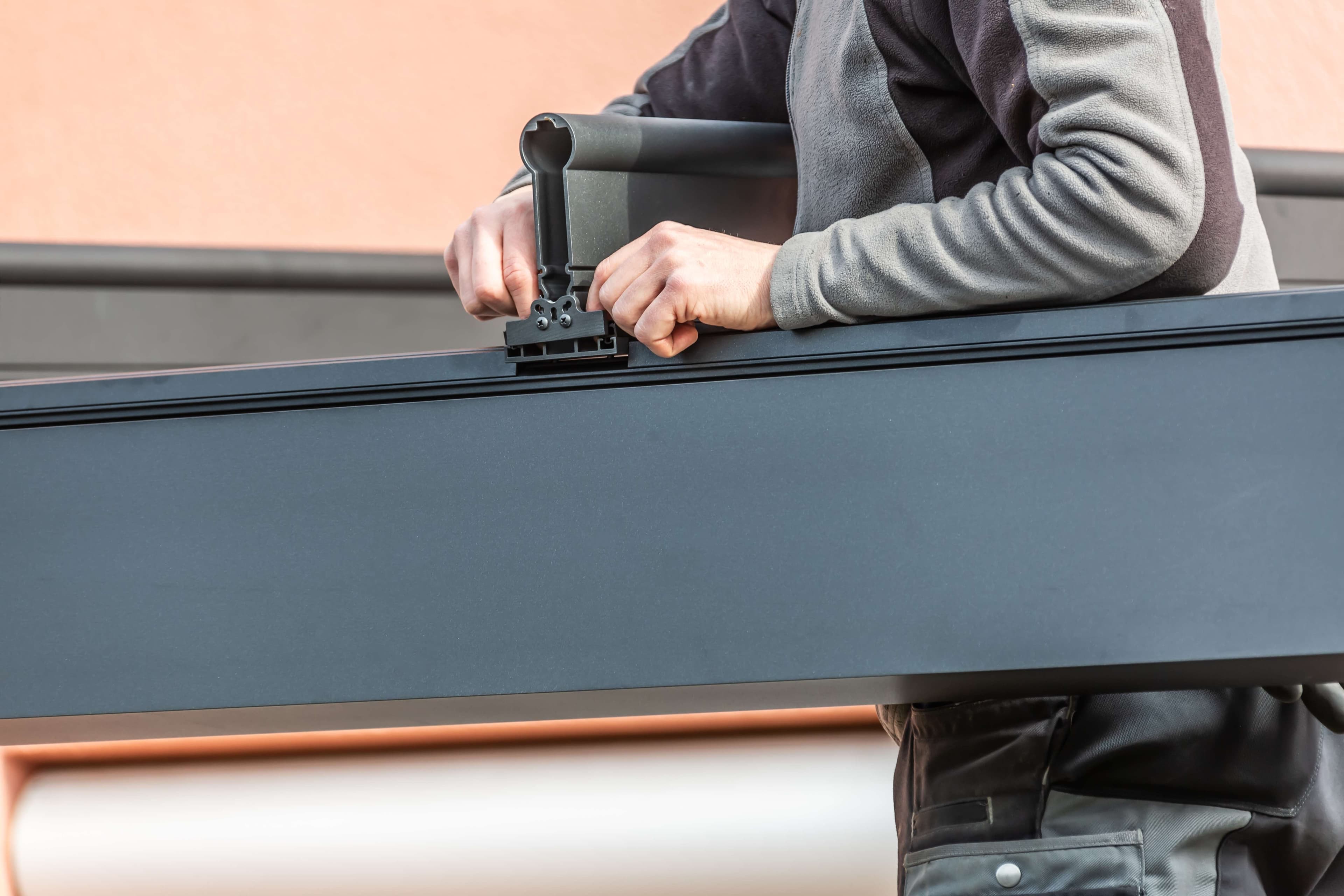 Installer attaching hardware to an aluminum pergola beam