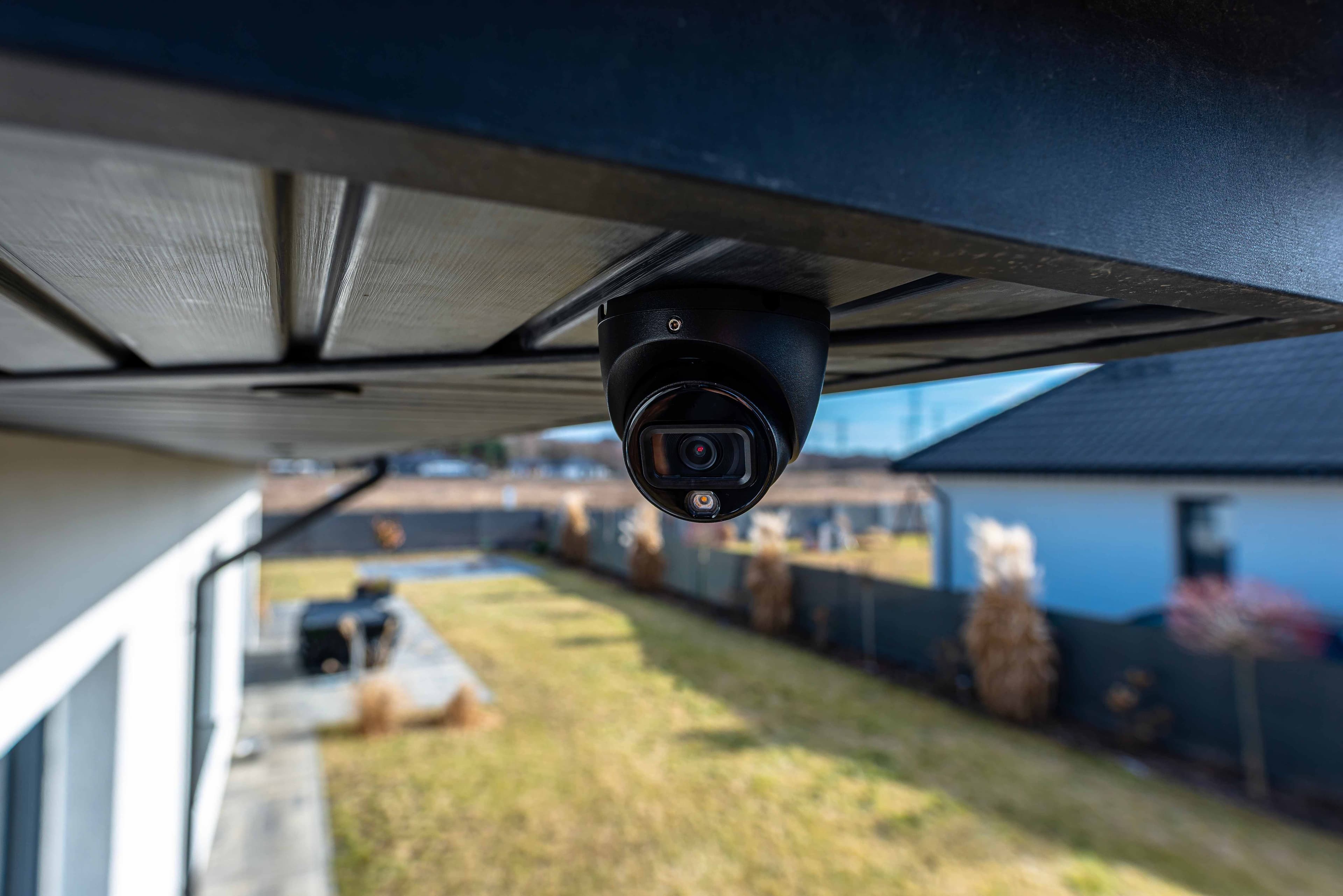 Black dome security camera mounted under a roof eave