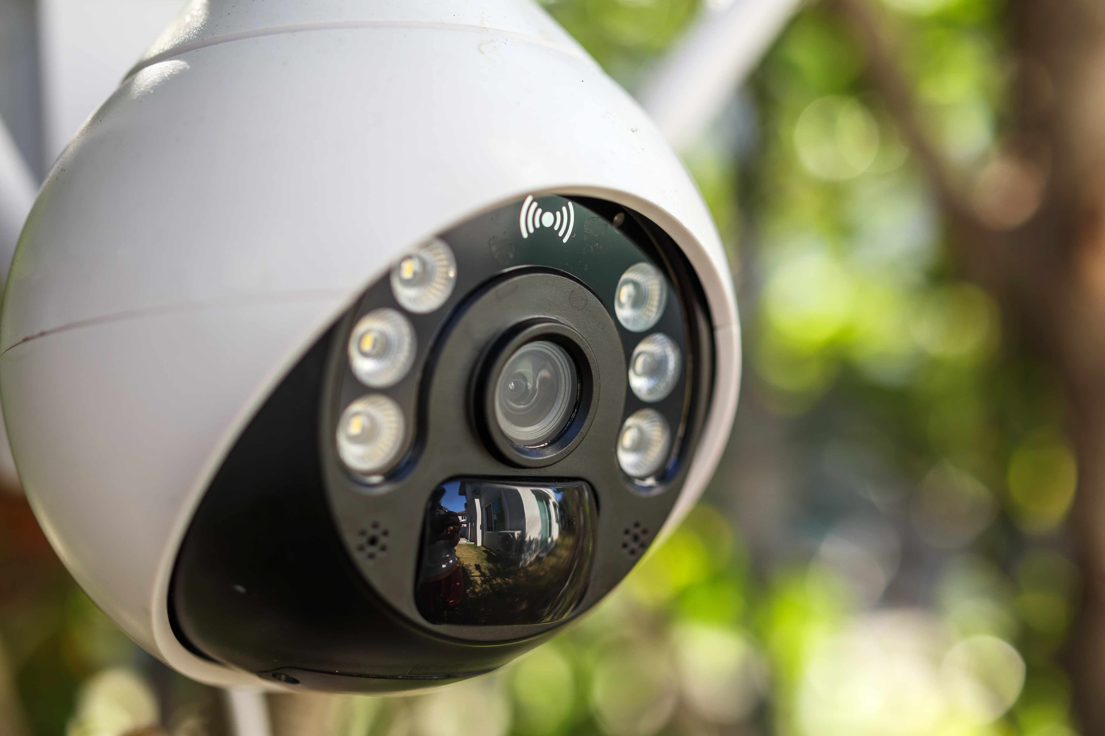 Close-up of a white outdoor security camera with infrared LEDs mounted outside a home.