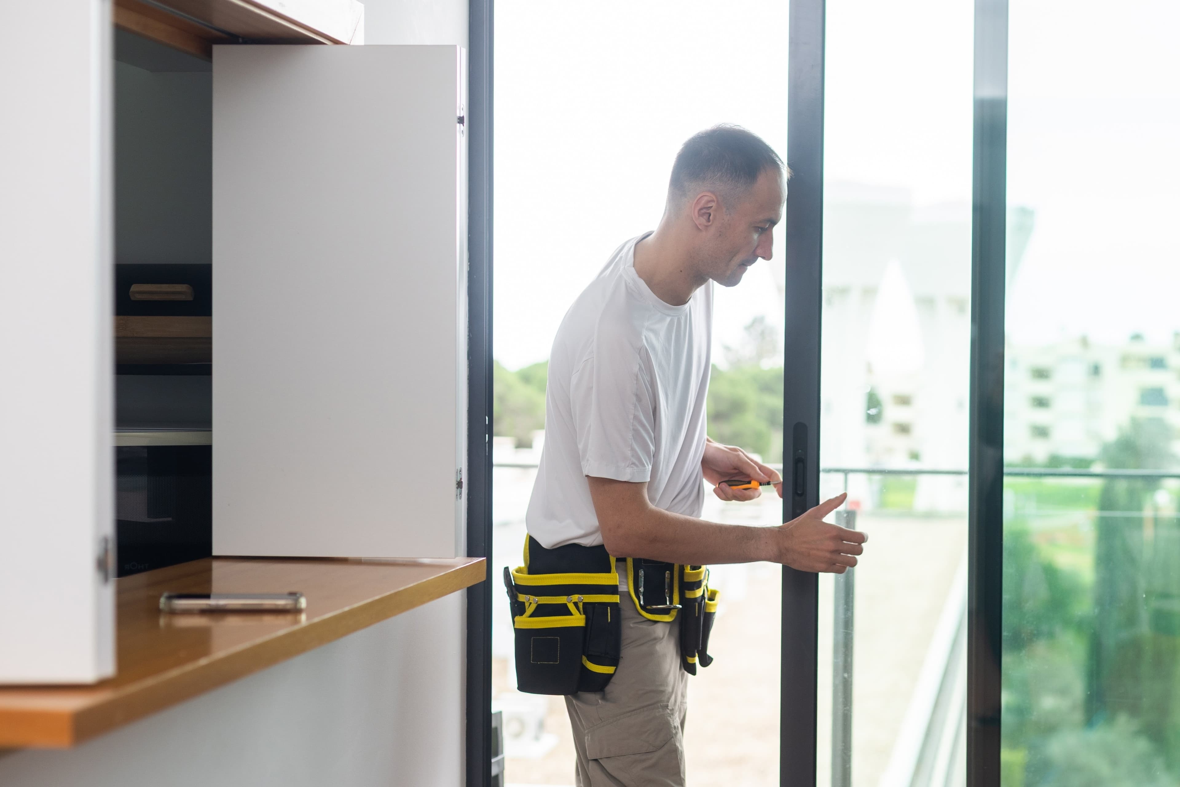 Technician adjusting the latch hardware on a sliding glass balcony door