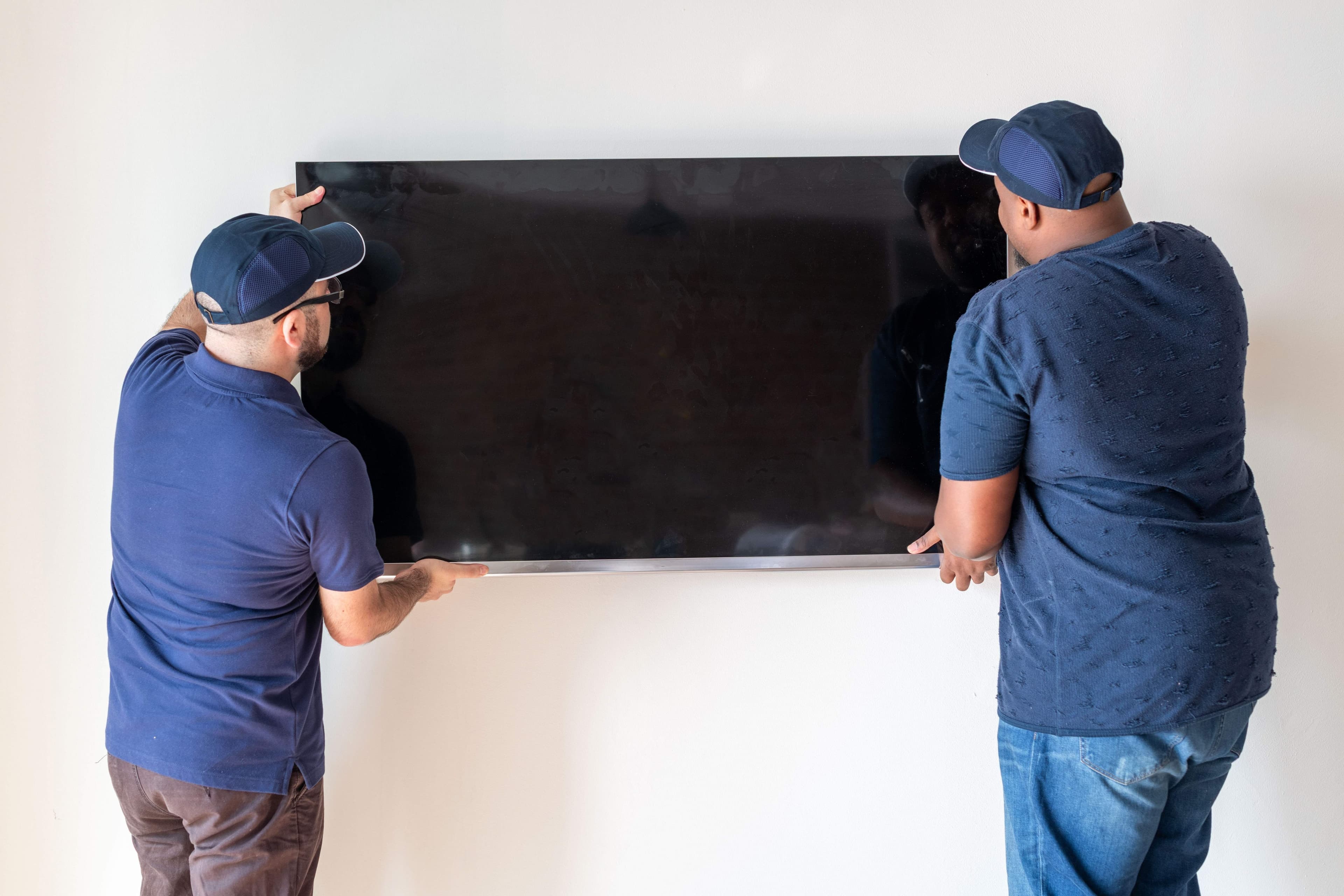 Two installers positioning a flat-screen TV on a wall mount