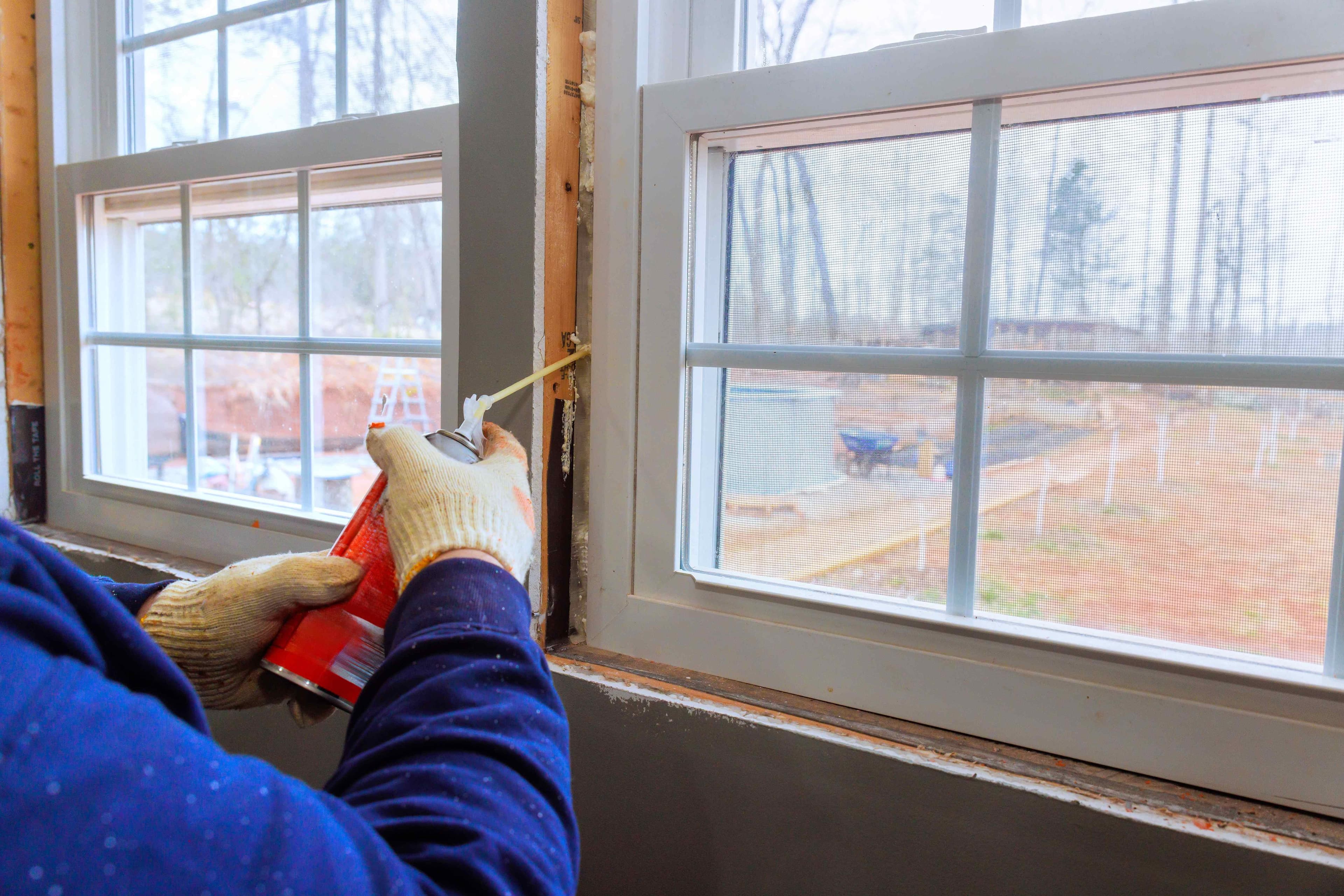 Hands pressing a new weatherstripping strip into a window track to help seal against drafts and gaps.