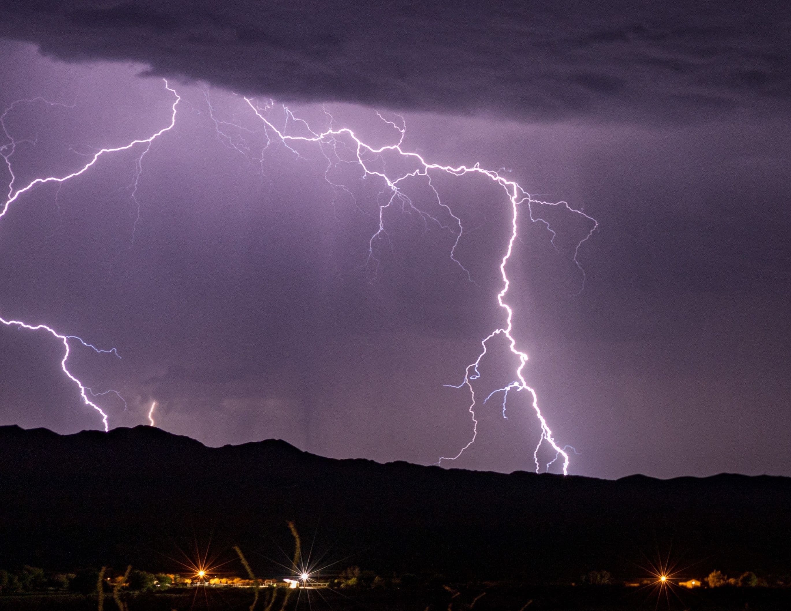 Lightning illuminating a severe thunderstorm over a dark landscape at night
