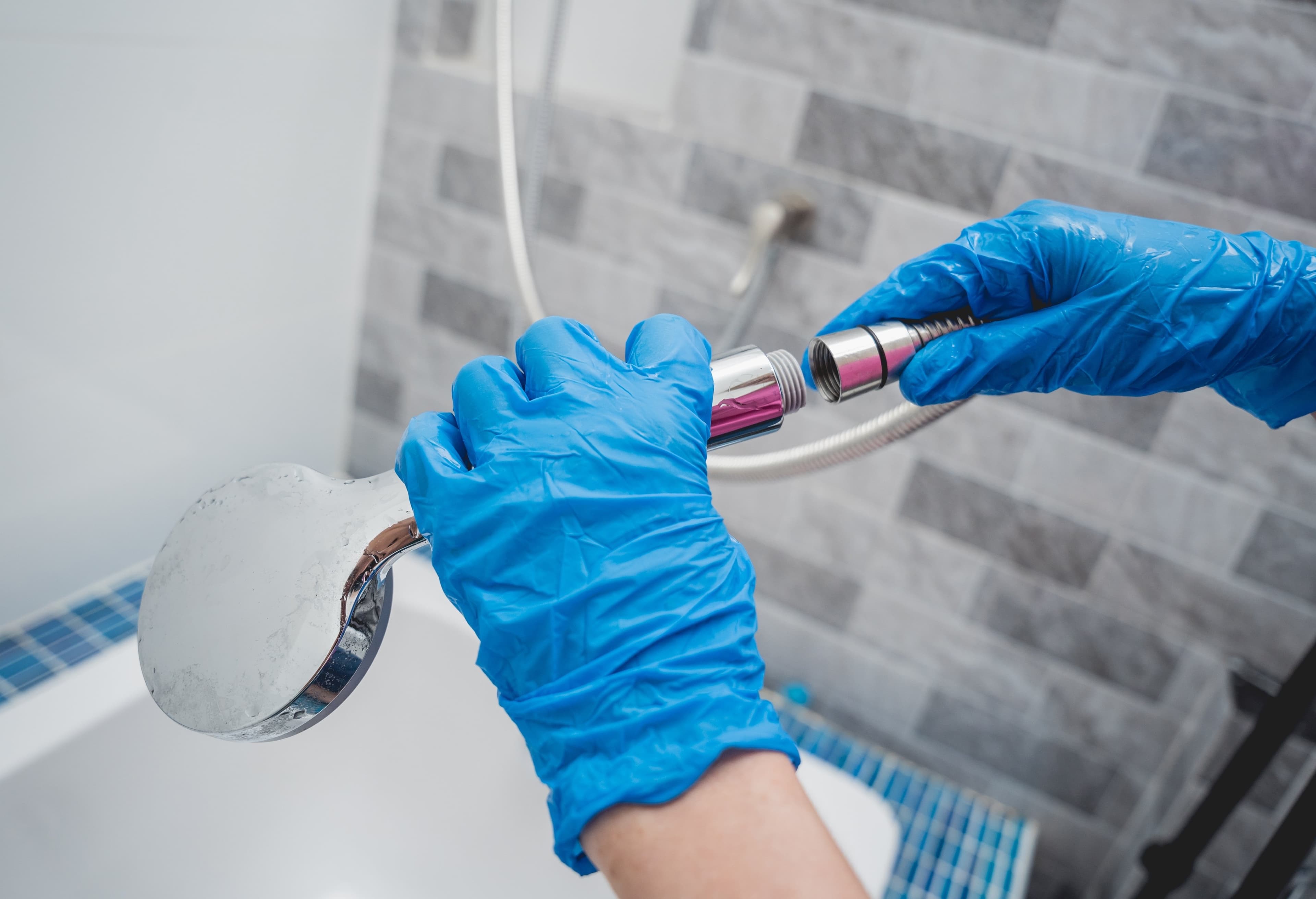 Technician repairing a bathroom faucet connection with protective gloves