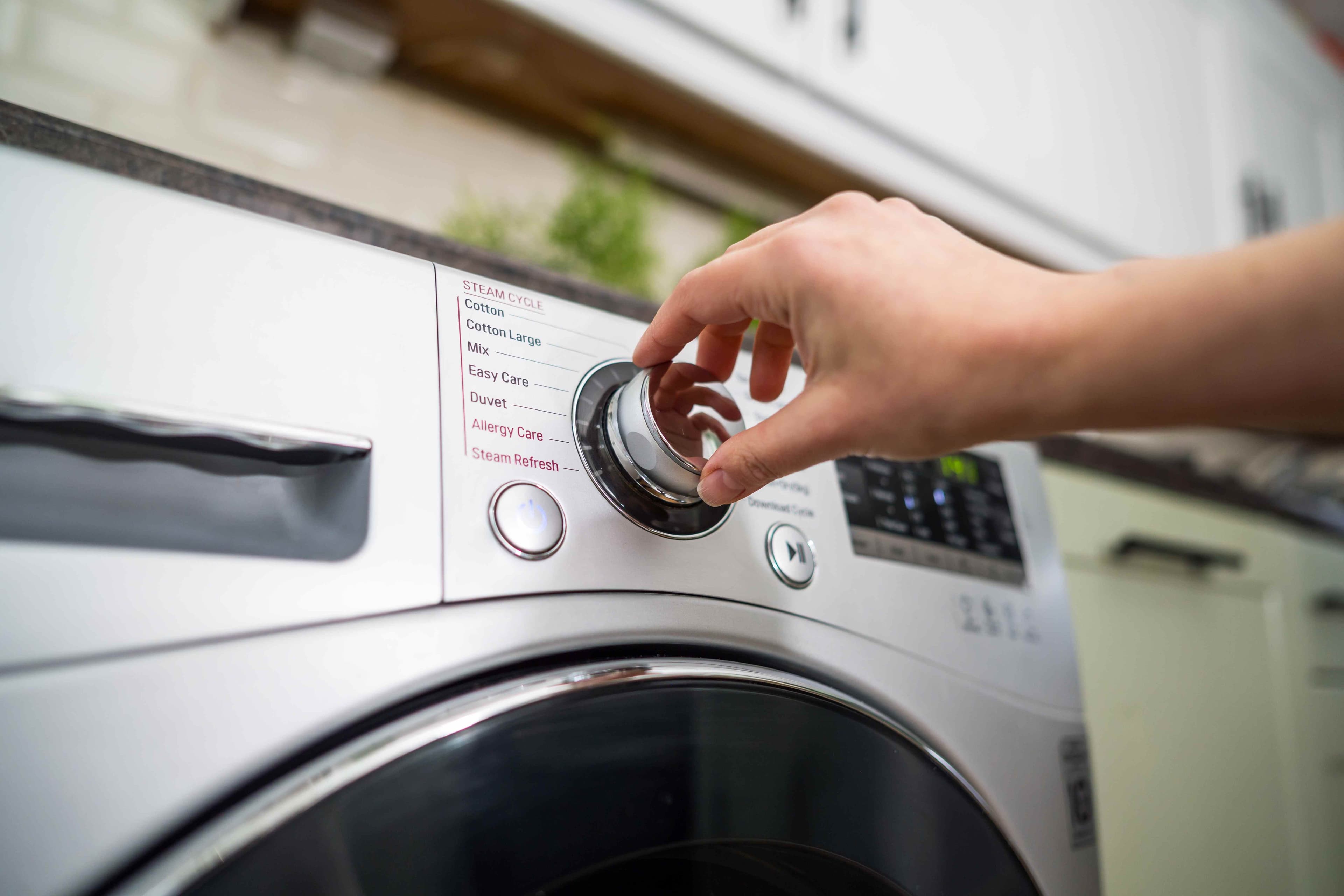 Hand adjusting a washing machine cycle dial during home maintenance