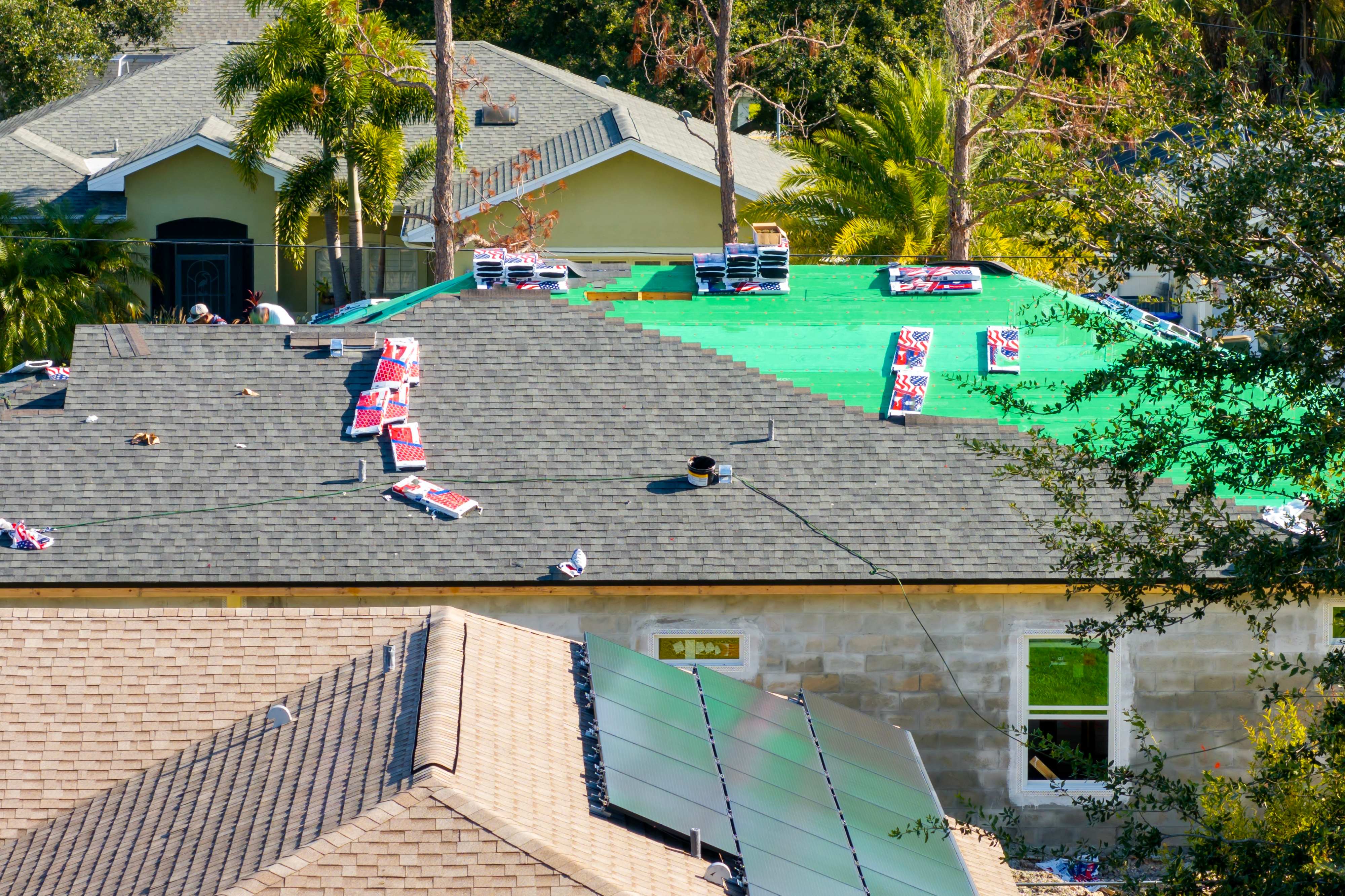 Roof replacement in progress with new roofing materials installed beside existing shingles